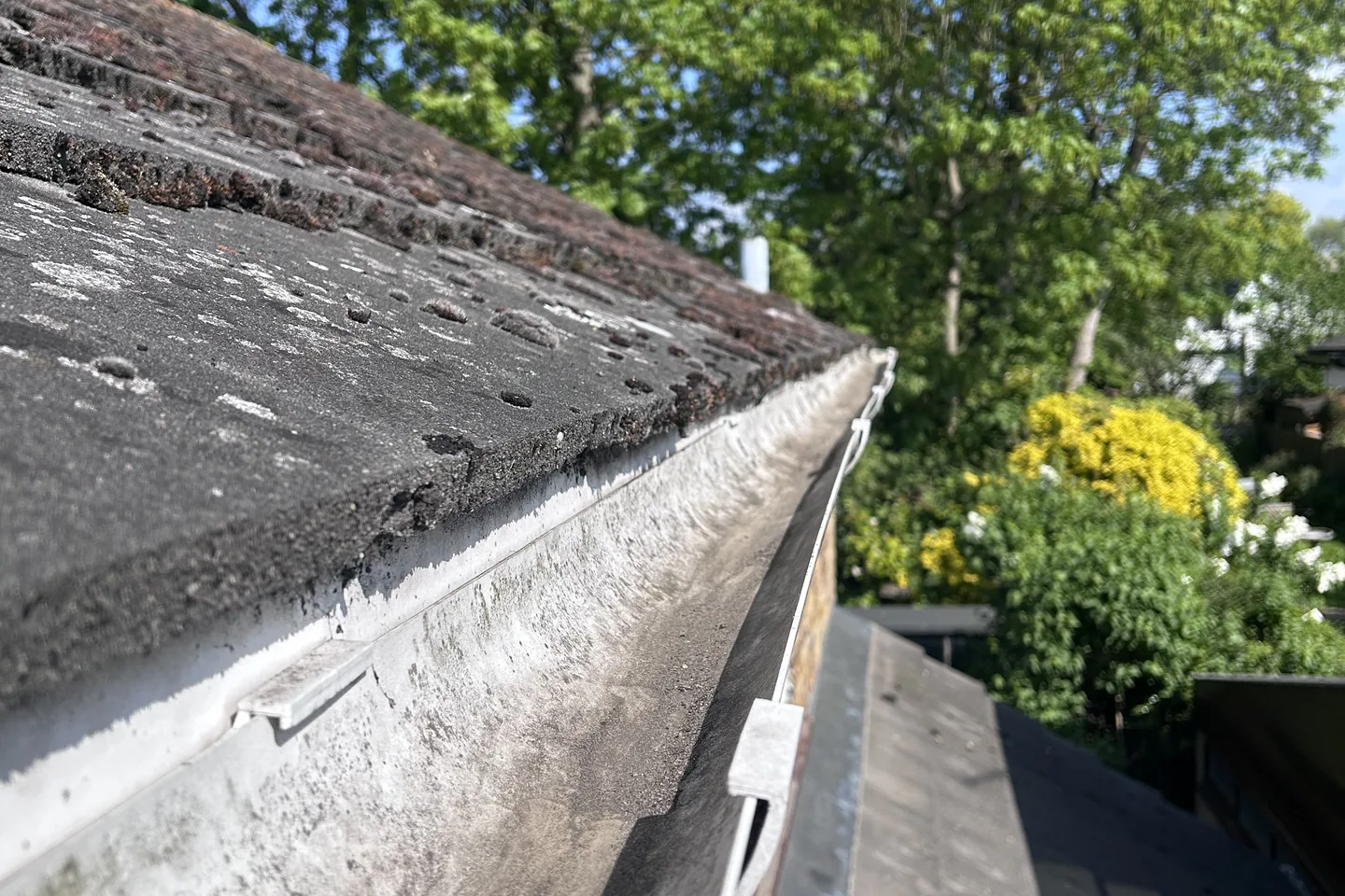A cleared gutter run along a tiled roof, photographed from the ladder-free camera pole
