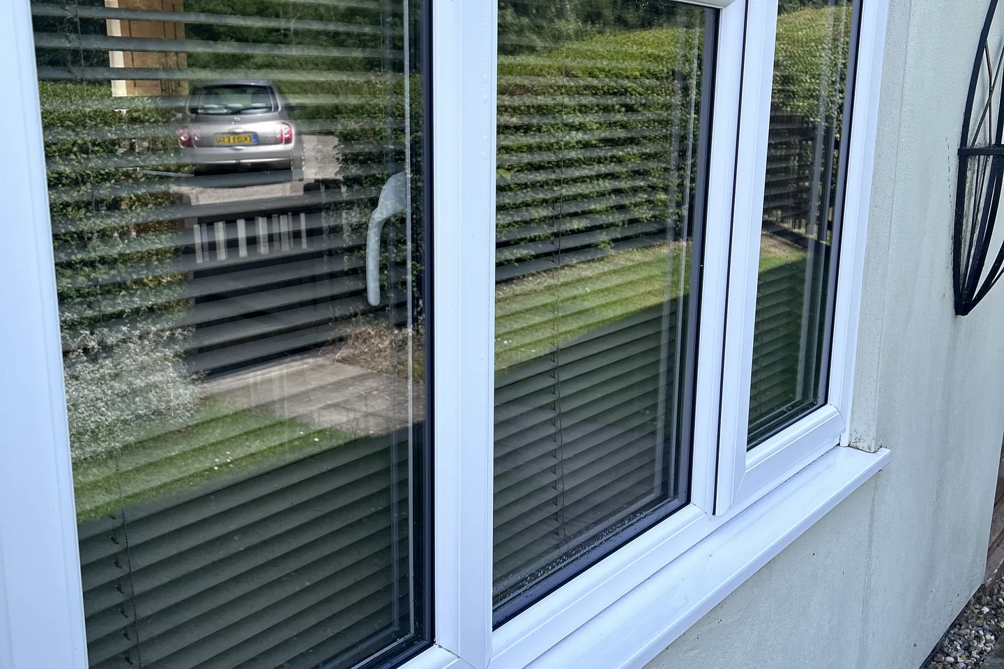 A cleaned uPVC window reflecting the garden behind the photographer