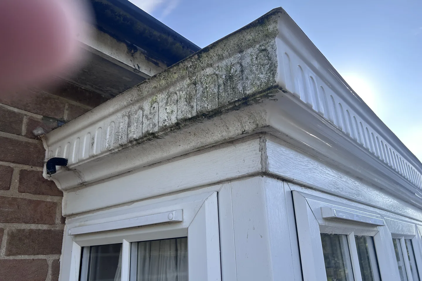 The corner of a uPVC fascia and soffit stained green with algae before cleaning