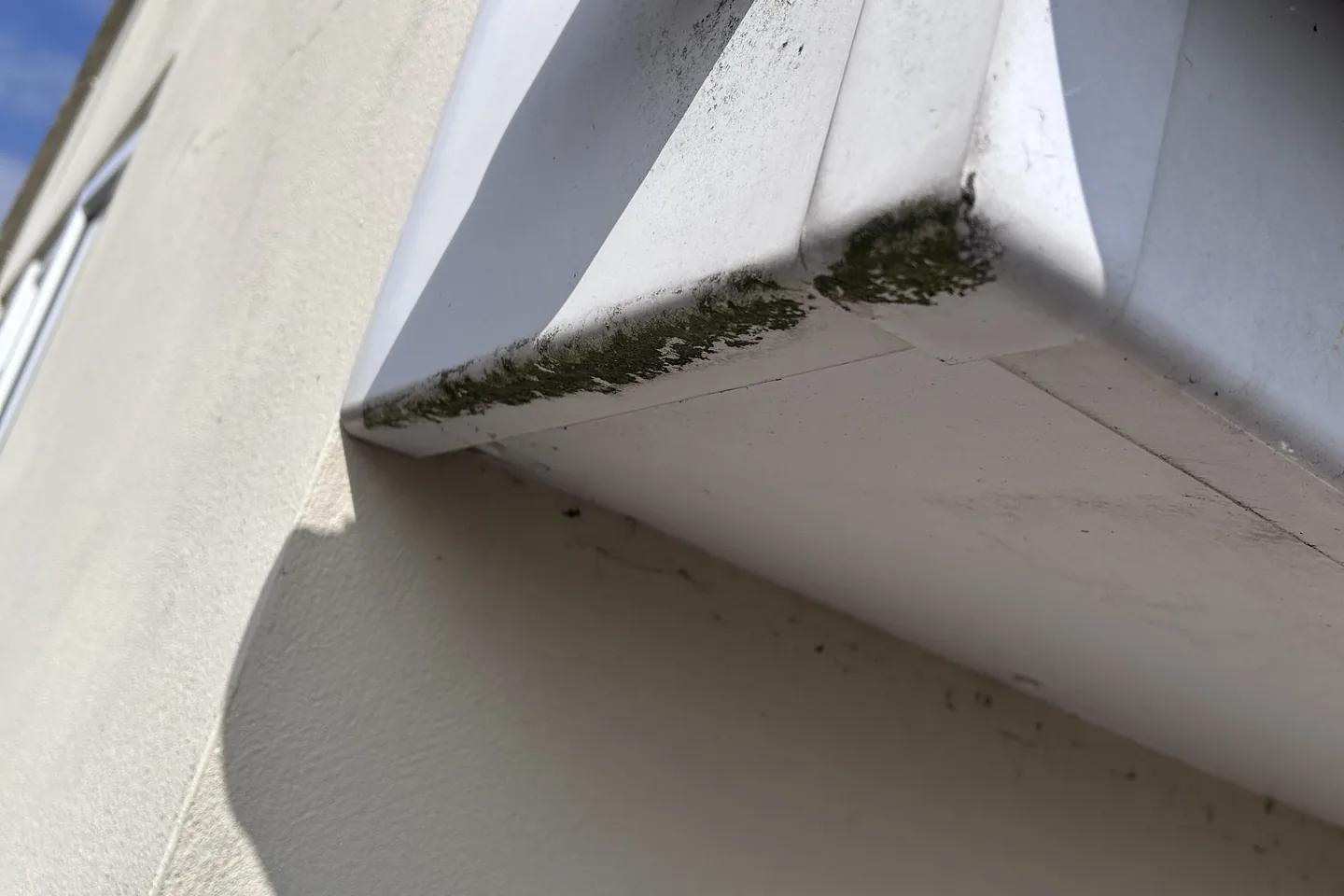Fascia and soffit boards along the roofline of a rendered house, freshly cleaned