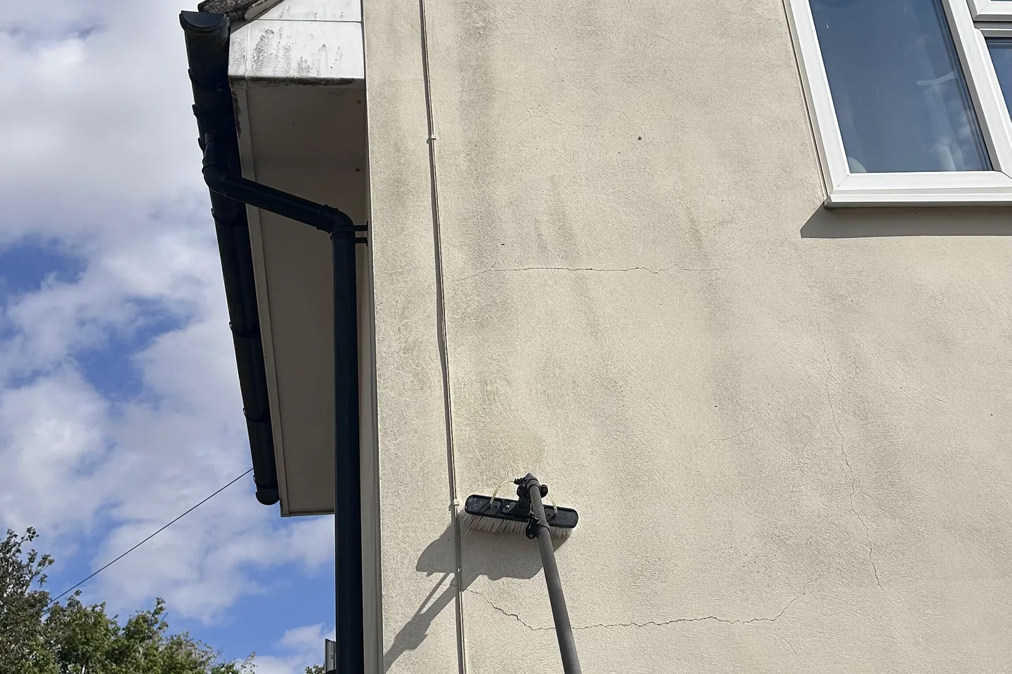 A rendered house being washed down from the ground with a reach pole
